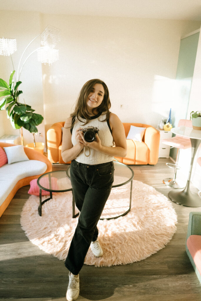 photographer holding a camera and smiling in a funky living room in Washington DC
